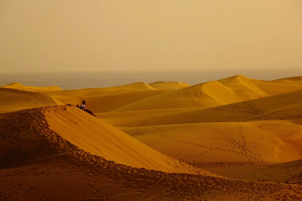 Niño dibujando con tiza en el tanque de una motocicleta en una gasolinera del desierto al atardecer